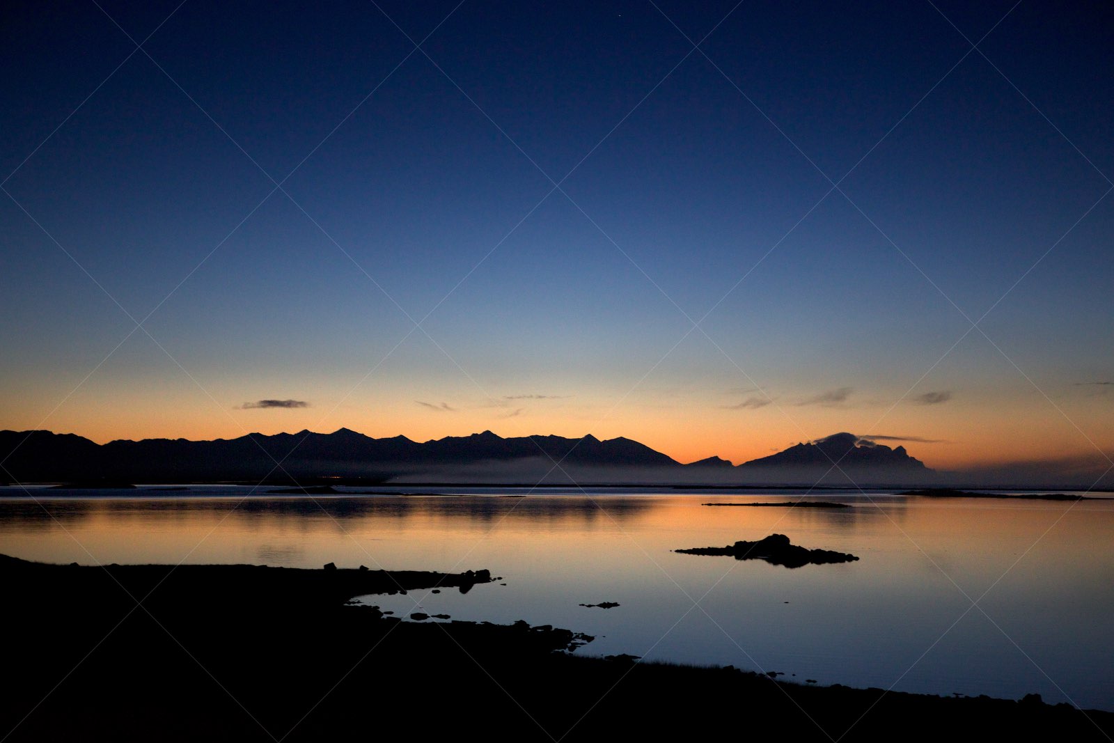 Sunset over calm waters with mountain silhouette in Iceland